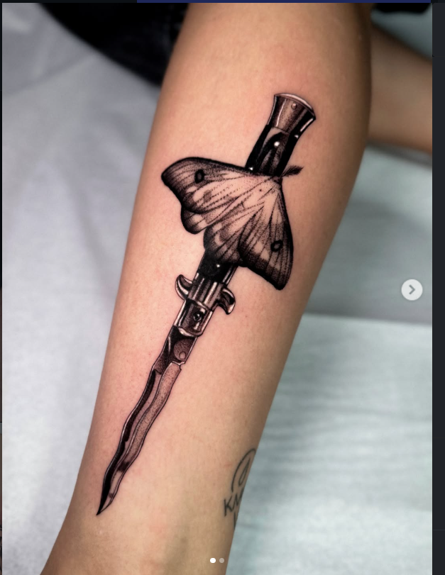 Blackwork dagger and moth tattoo on forearm